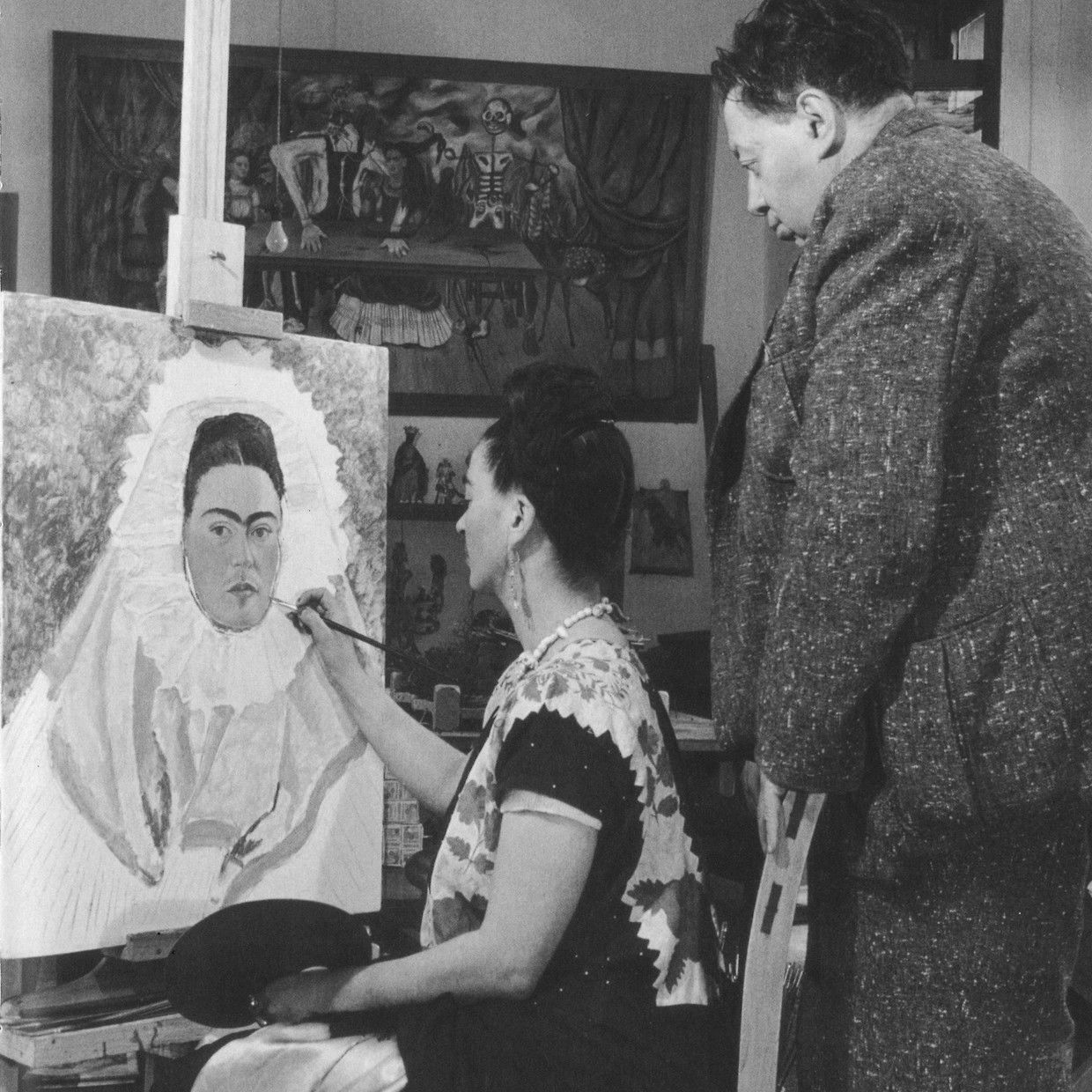 Frida Kahlo werkt aan een zelfportret, terwijl haar grote liefde Diego Rivera toekijkt