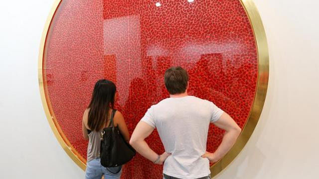 Artwork by Damien Hirst with many red dots at an art fair